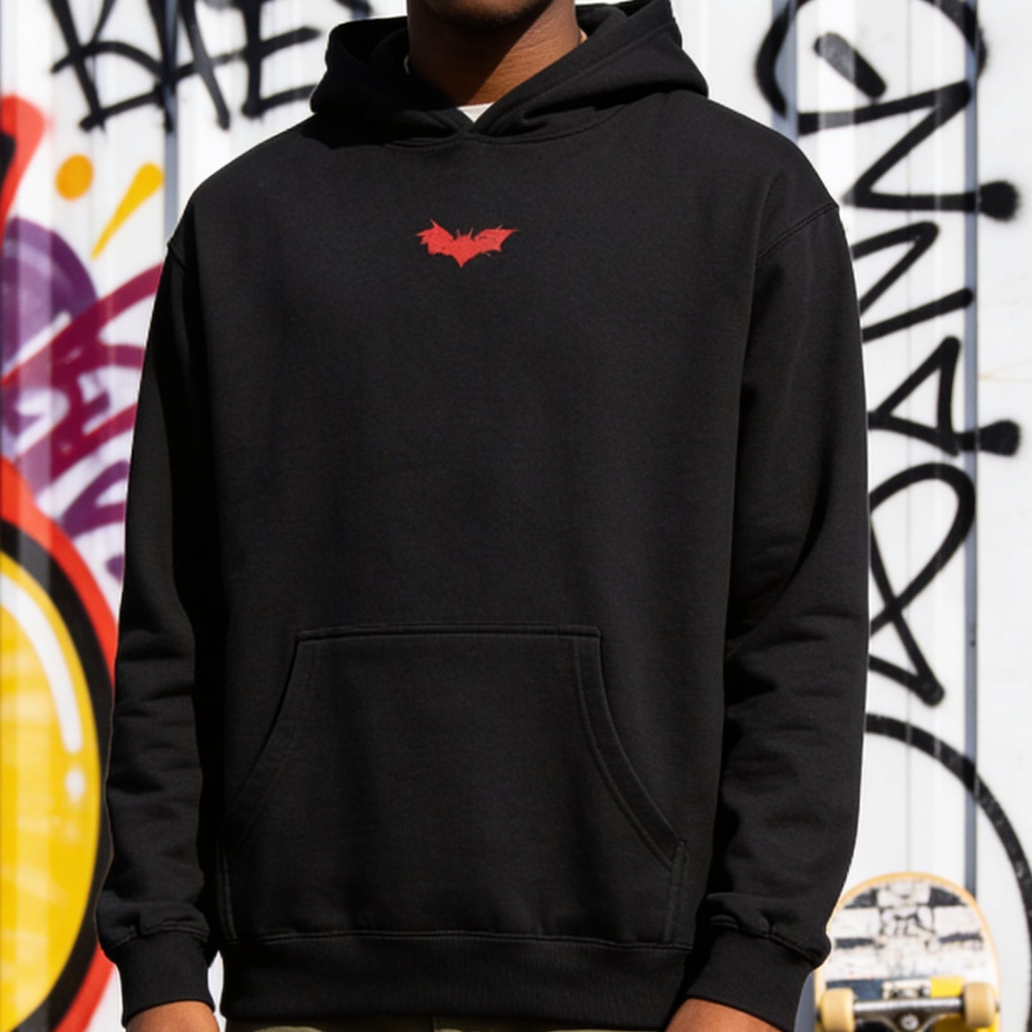 Person wearing a black hoodie with a red logo against a graffiti-covered wall.