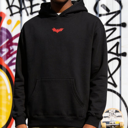 Person wearing a black hoodie with a red logo against a graffiti-covered wall.